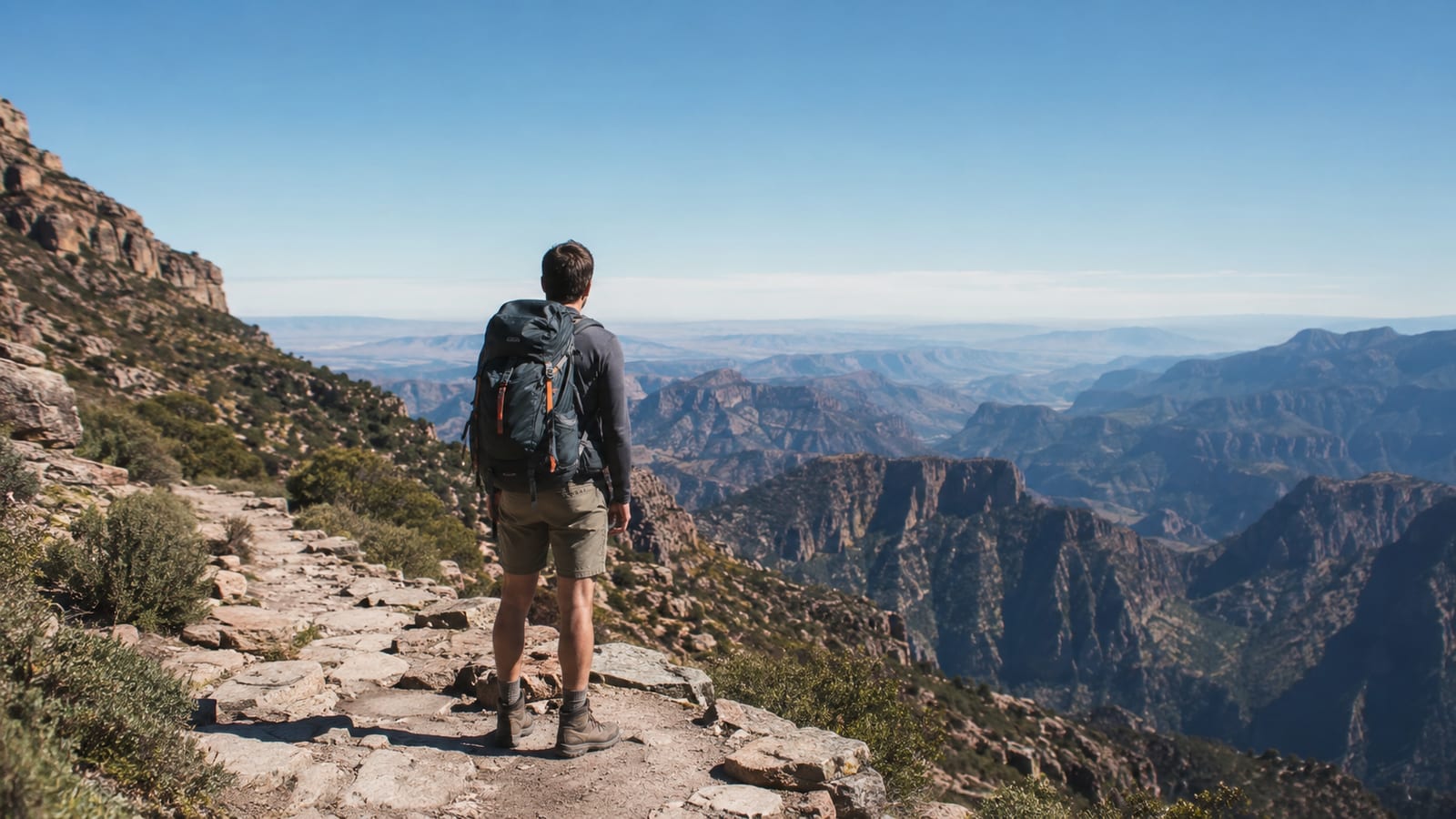 Hiker in boots standing on rocky alpine terrain overlooking mountain vista