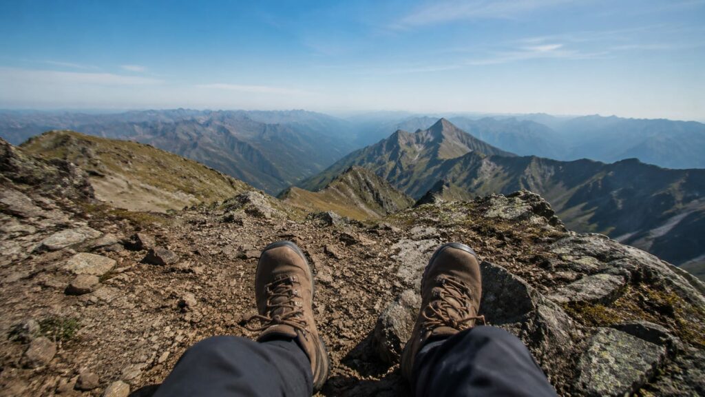 Hiker's boots on rocky trail terrain, demonstrating proper hiking footwear fit