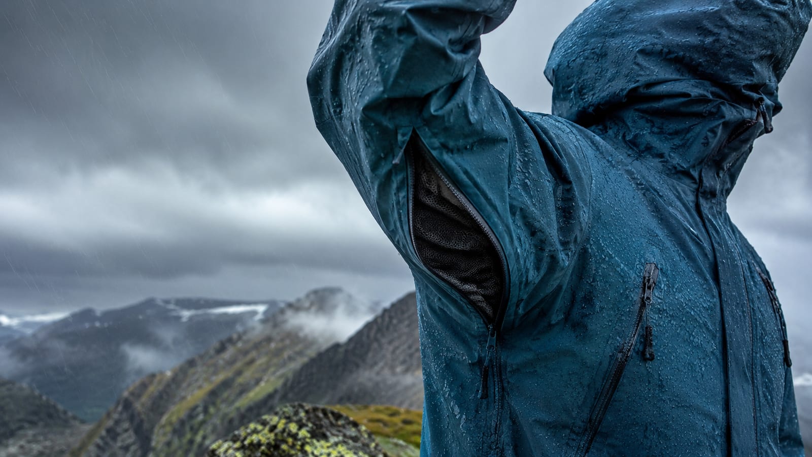 Close-up of rain jacket pit zips and hood adjustments releasing moisture during heavy rain